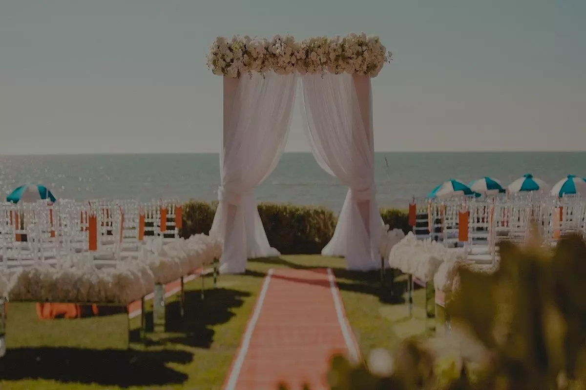 A wedding ceremony with white flowers and pink chairs.