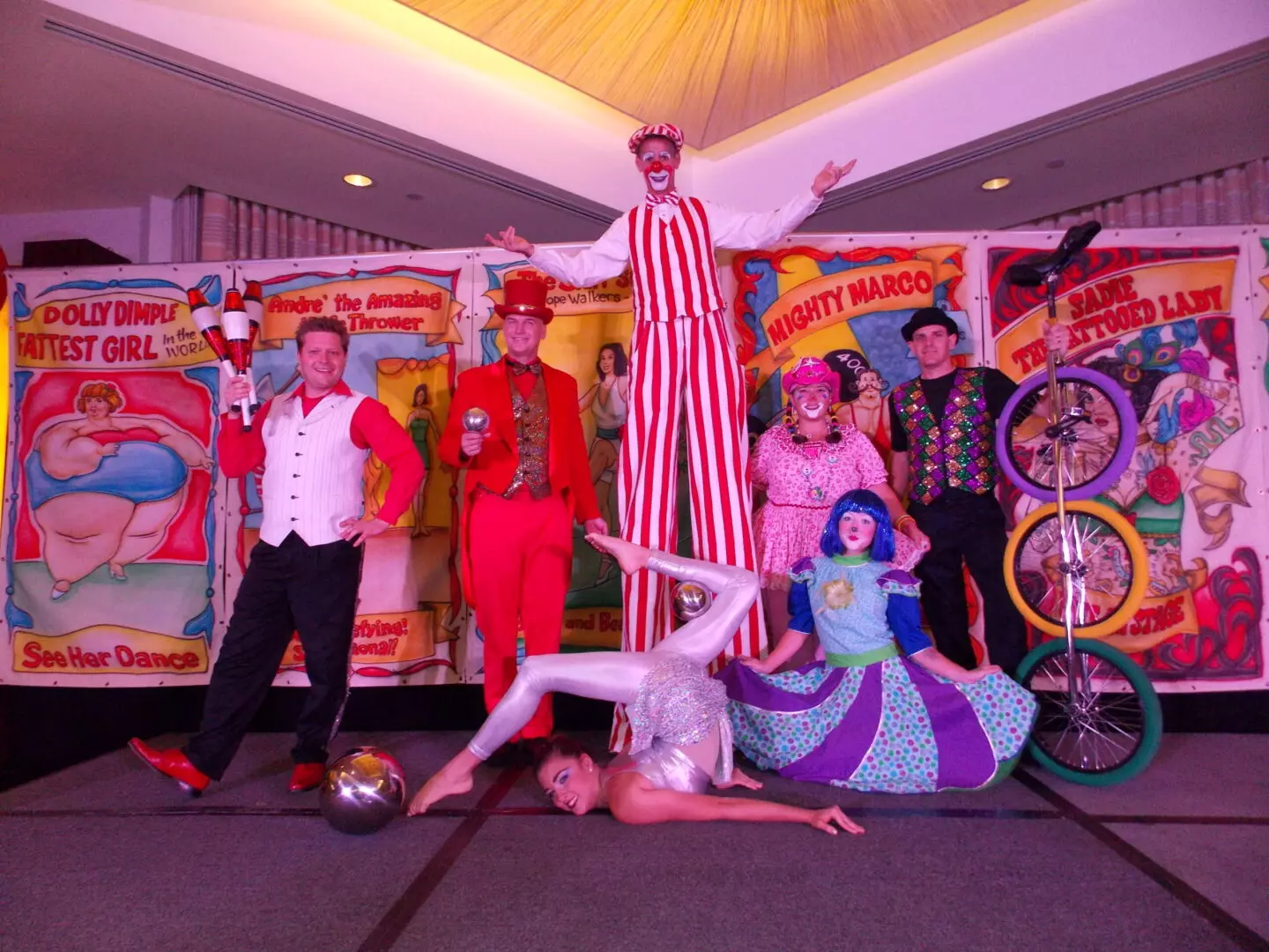 A group of people standing around in front of circus posters.