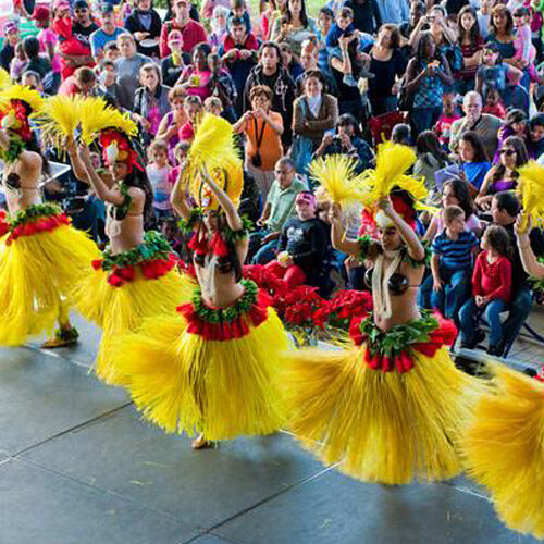 A group of hula dancers in yellow and red skirts.